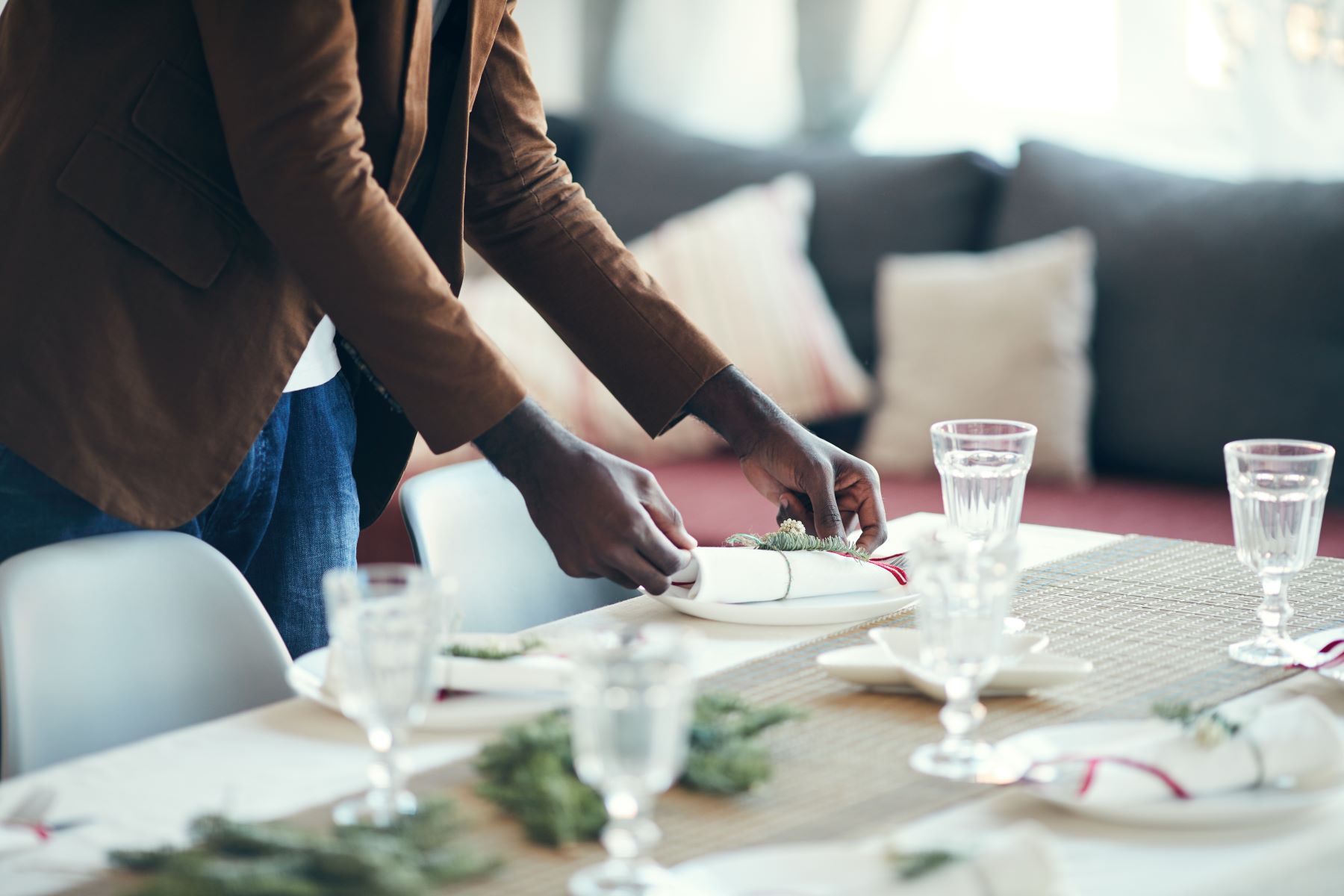 A Black man places a plate at a dining table