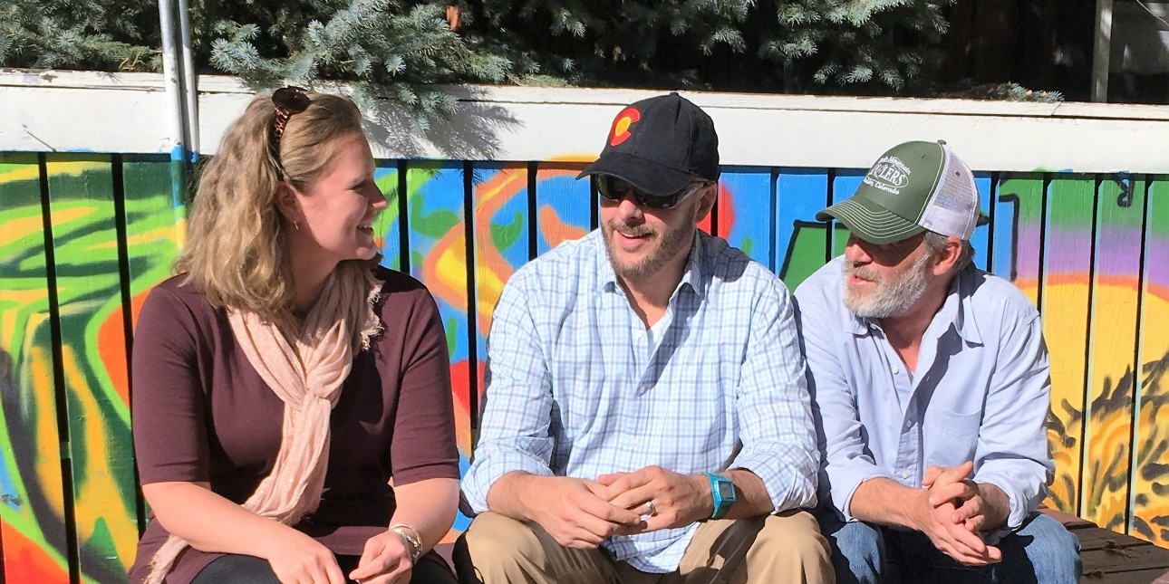 Three people sitting on picnic table talking