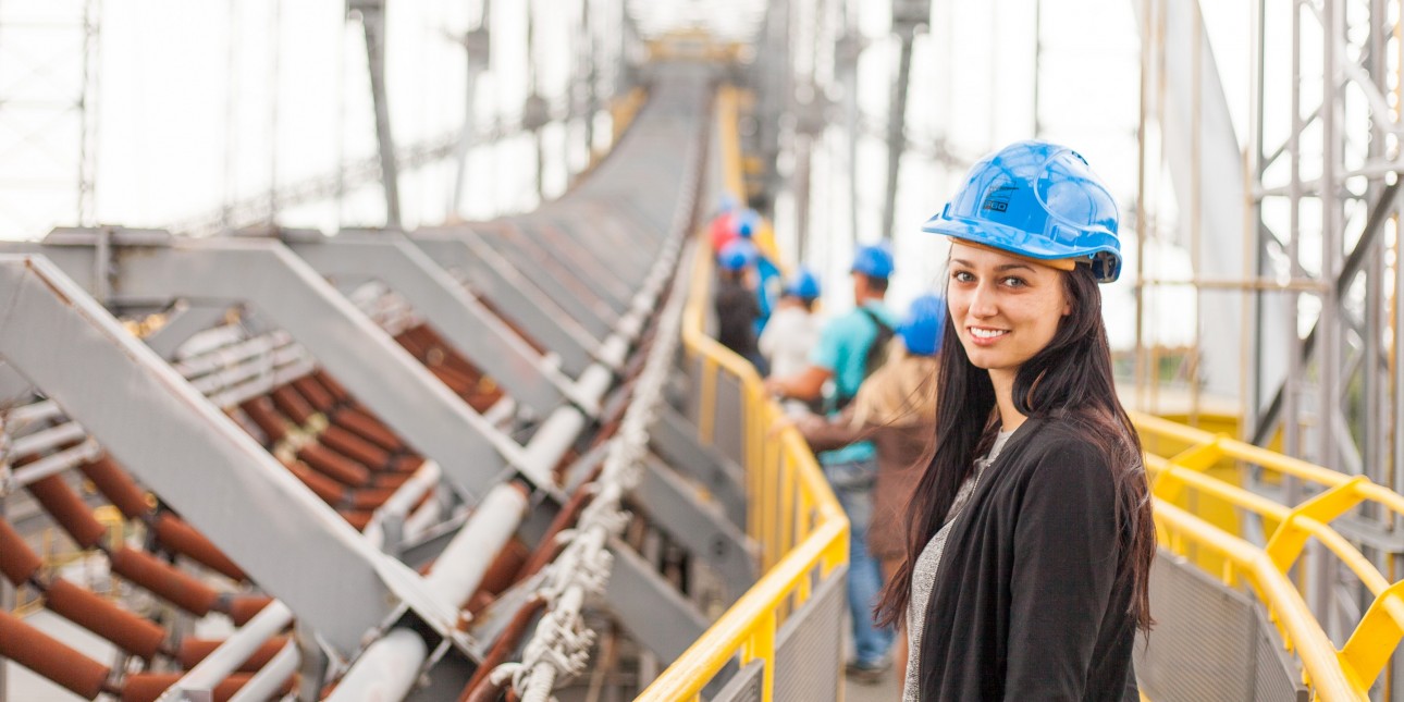 Woman in hard hat standing on bridge.