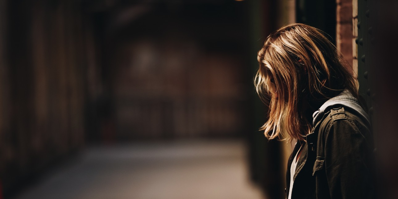 woman with head down leaning against wall