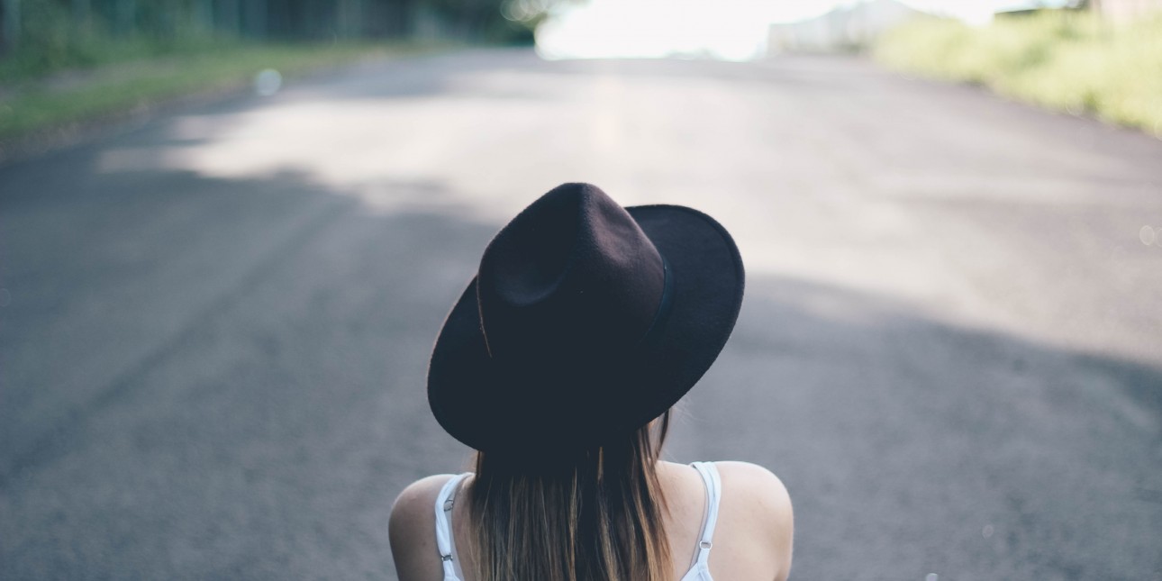 woman sitting on road wearing black hat