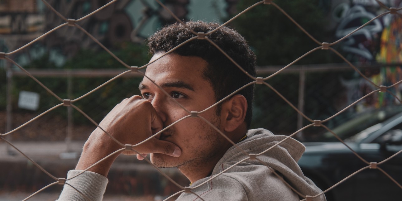 Man looking into the distance behind a fence