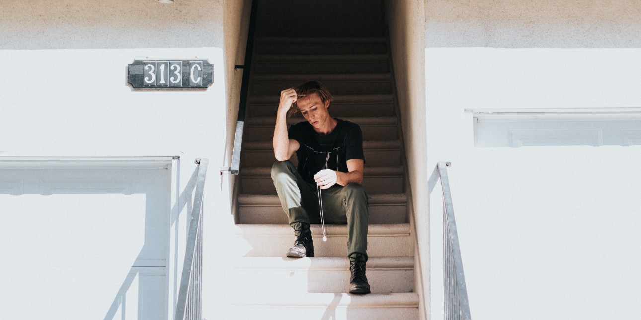 young person sitting on steps leading into building