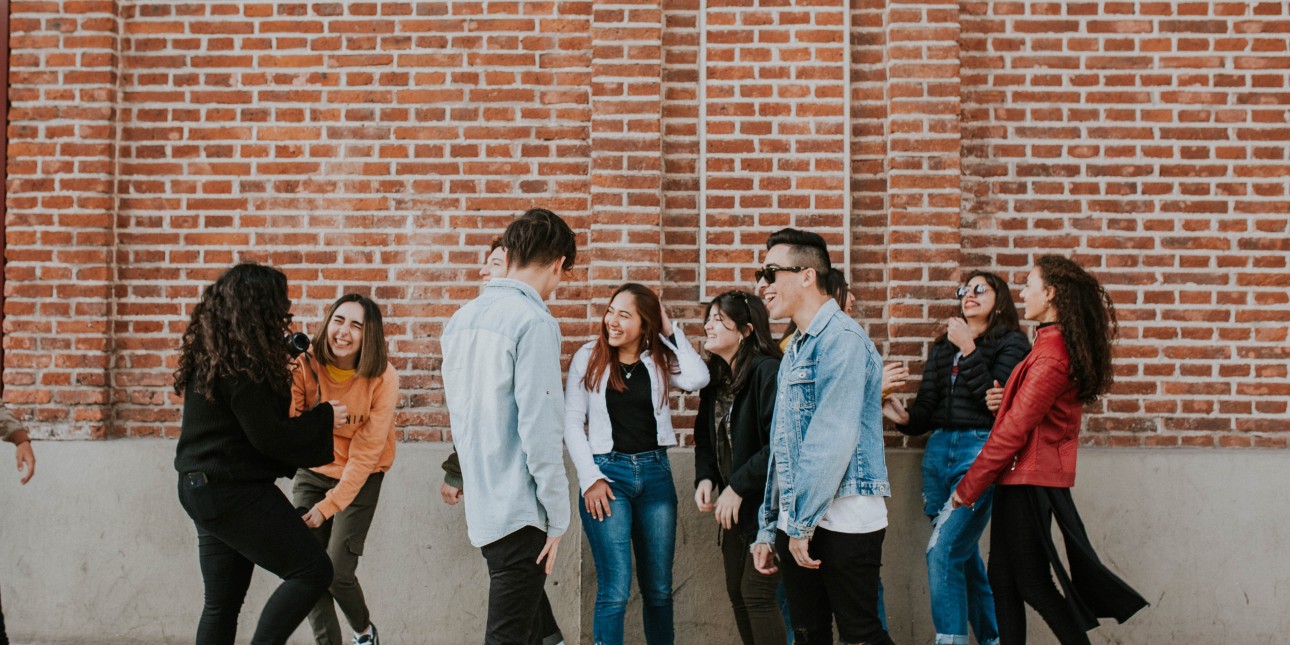 a group of young adults next to a brick wall