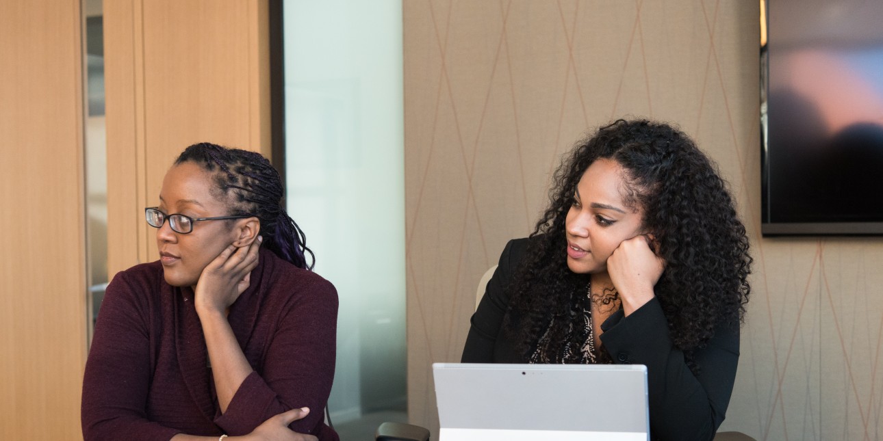 two Black women sitting at a conference table 