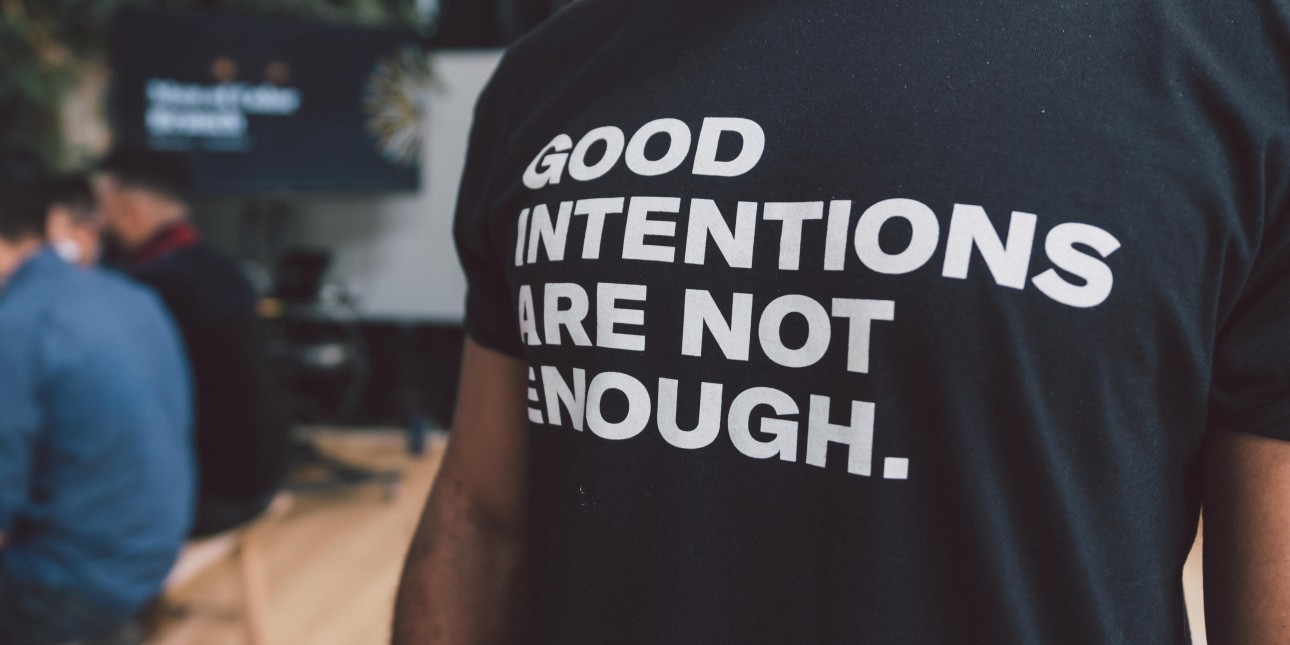 a black tshirt that reads "GOOD INTENTIONS ARE NOT ENOUGH" in white text