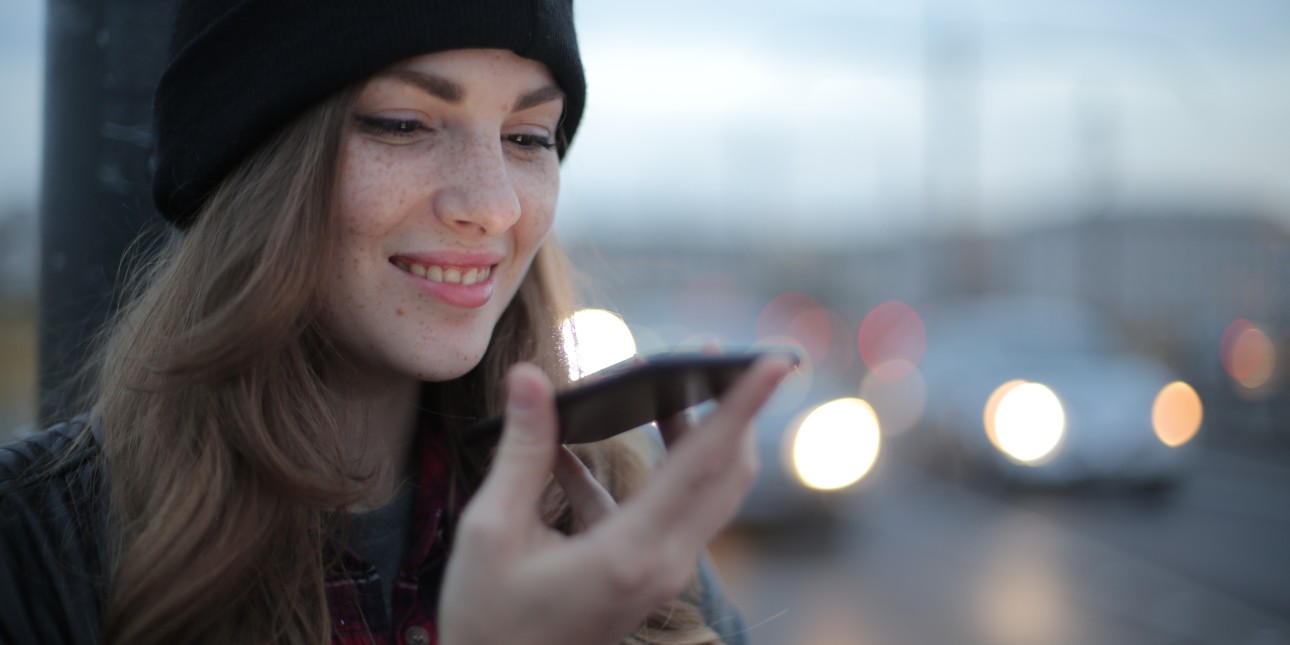 young person wearing a beanie, talking into a phone