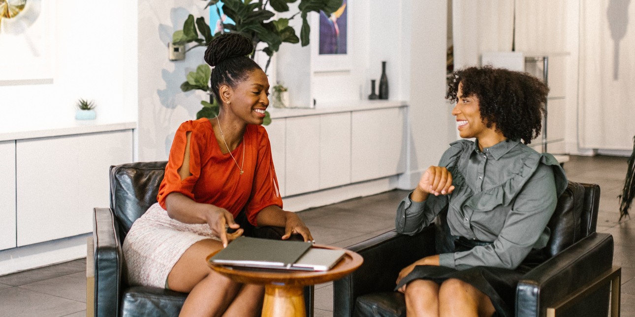 two Black women sitting at a table talking