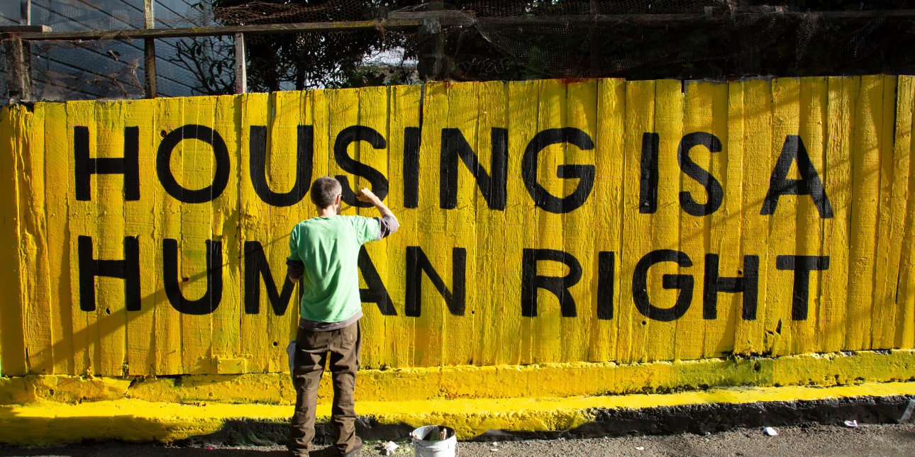 Housing is a human right sign being painted on fence