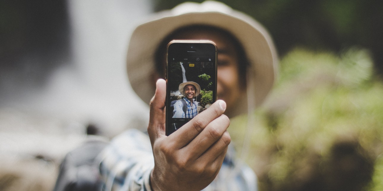 a young person wearing a brown hat taking a selfie