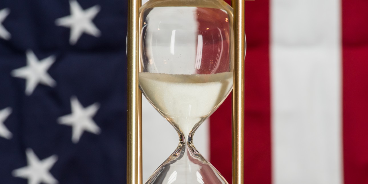 US flag with an hour glass in the foreground
