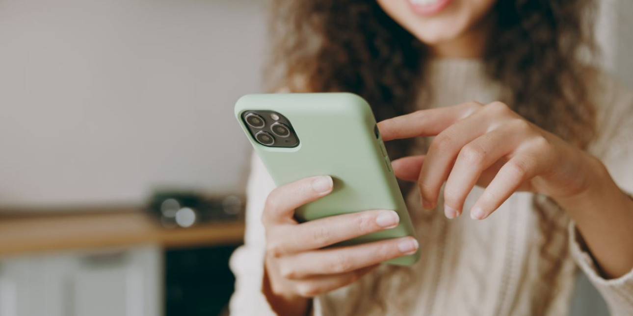 Cropped young smiling woman wearing casual clothes sweater using a mobile phone