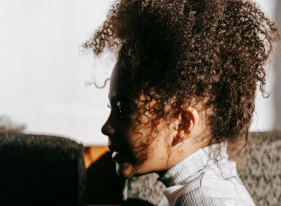 young Black girl in profile looking to the left with curly hair on top of their head