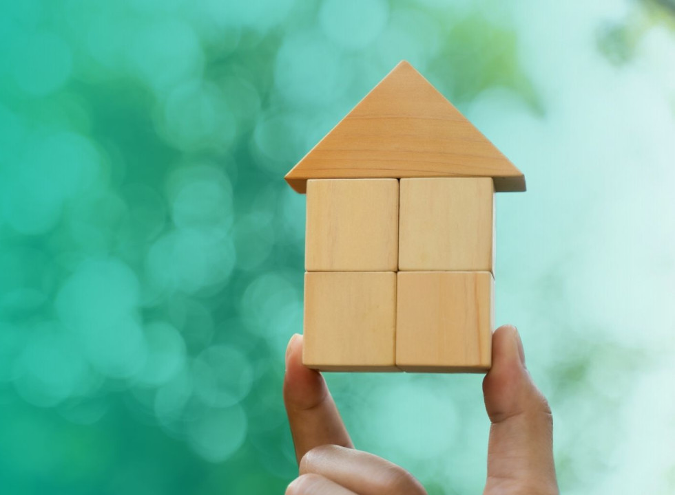 A building-block house being held up by a hand.