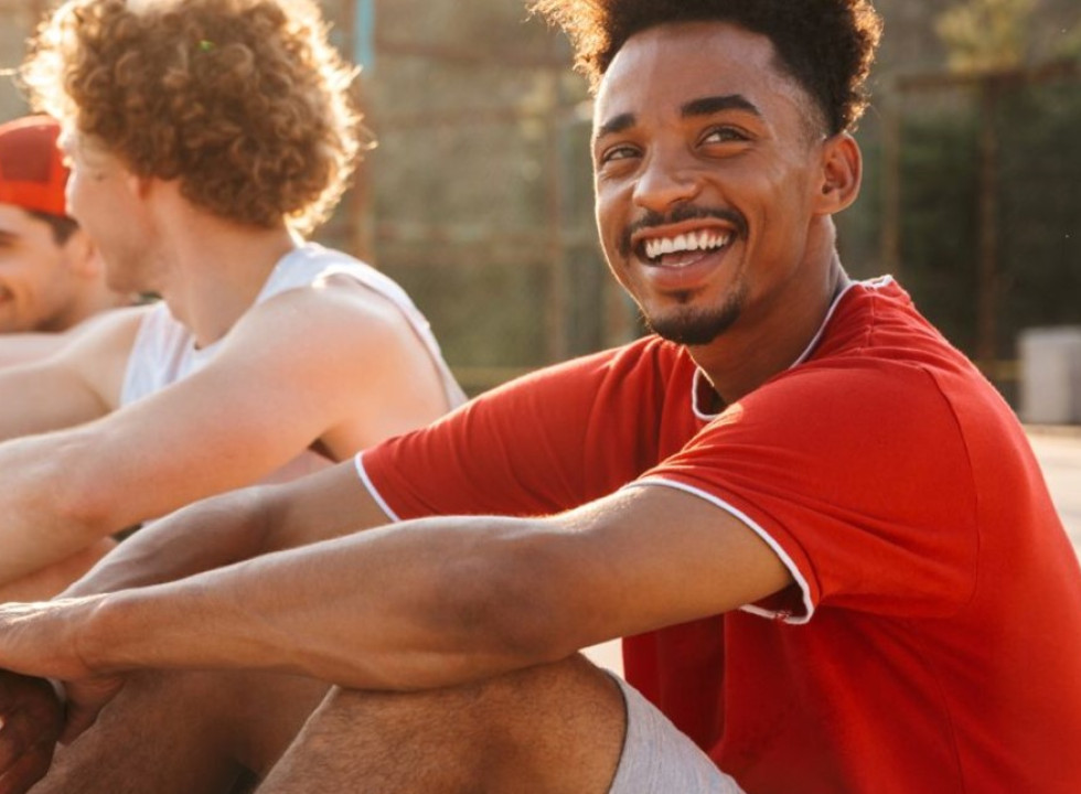 Young men on a basketball court, one in the foreground smiling