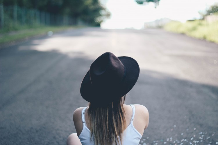 woman sitting on road wearing black hat