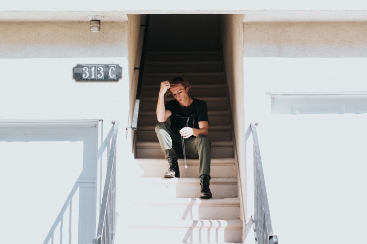 young person sitting on steps leading into building