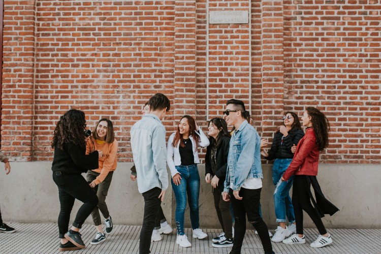 a group of young adults next to a brick wall