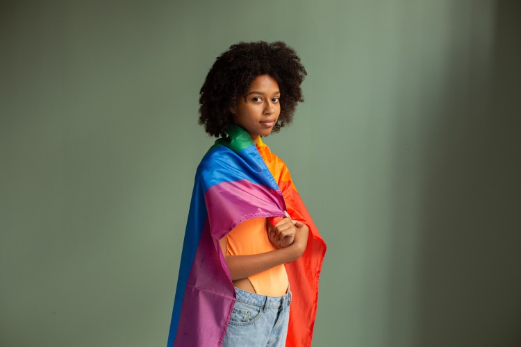 young person with a pride flag over their shoulder
