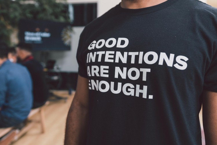 a black tshirt that reads "GOOD INTENTIONS ARE NOT ENOUGH" in white text