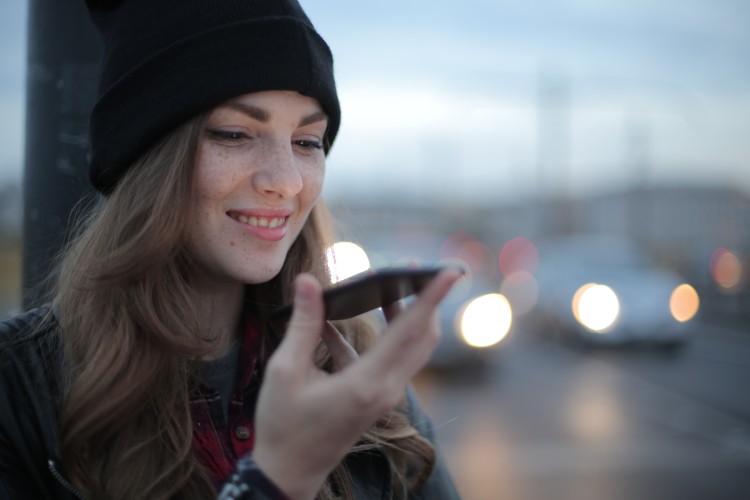 young person wearing a beanie, talking into a phone