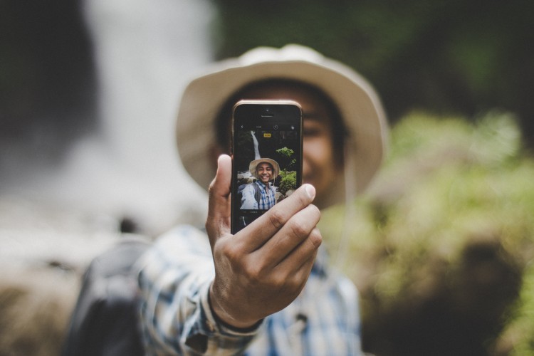 a young person wearing a brown hat taking a selfie