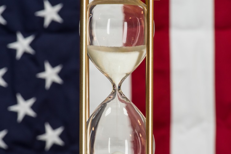 US flag with an hour glass in the foreground