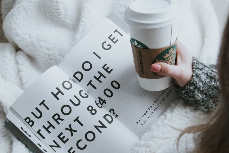 a young person drinking coffee and reading a magazine -by David Lezcano on Unsplash