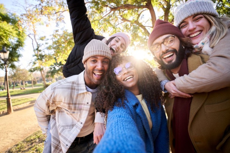 Photo portrait of cheerful group of friends taking smiling selfie looking camera. Young people having fun together outdoors at park in winter time