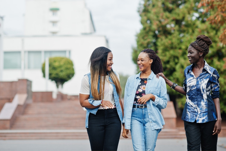 Three Black women walking and talking together.